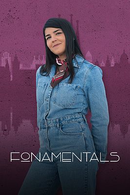 A young woman in a denim jumpsuit and a neckerchief, with several purple-toned buildings behind her.
